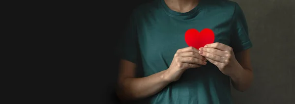 Red heart in hands. Banner with black background. Young lady giving her love concept photo