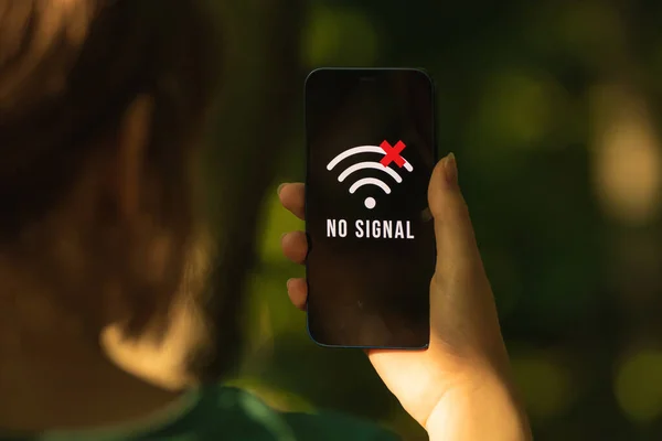 Servis ekranı olmayan bir cep telefonu, ormanda cep telefonu arayan bir kadın.