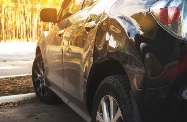 Yolda kaza üstüne kaza yapan siyah bir araba. Park yerinde kırık bir araba.