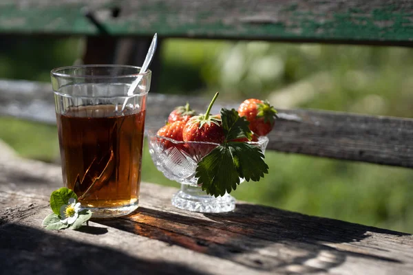 Cup of tea and wild strawberries on a wooden background — Stock Photo, Image