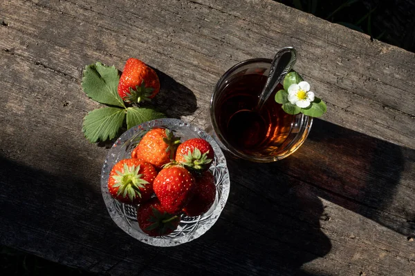 Cup of tea and wild strawberries on a wooden background — Stock Photo, Image