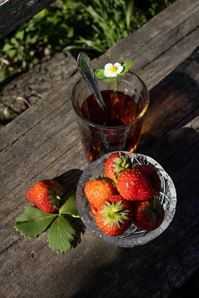 Cup of tea and wild strawberries on a wooden background — Stock Photo, Image