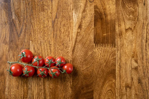 Background with red cherry tomatoes on the wooden table.
