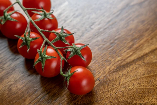 Background with red cherry tomatoes on the wooden table.