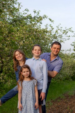 Çiçekli elma ağaçlarının arasında gezen güzel bir aile. Dört kişilik mutlu bir grup taze doğayla eğleniyor. Ruh hali konsepti