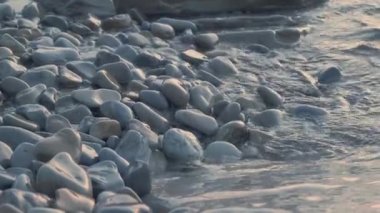 Dalgalarla yıkanan çakıl taşı plajına yakın. Deniz kıyısındaki ıslak taşlar boş çakıl plajlarını deniz suyuyla yıkıyorlar. Glare, plaj, yaz, tatil, tatil, seyahat, doğa, turizm konsepti