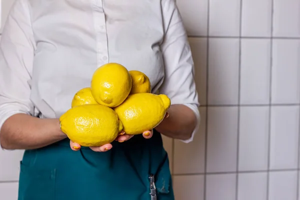 Beyaz arka planda kızın ellerinde büyük sarı limonlar var. Vejetaryen diyetleri için sulu meyveler. Sağlıklı yaşam tarzı restoranı, ev konsepti