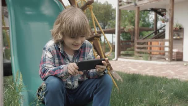 Barn Använder Smarttelefon Online Lekplatsen Pojke Tittar Rolig Video Bärbar — Stockvideo