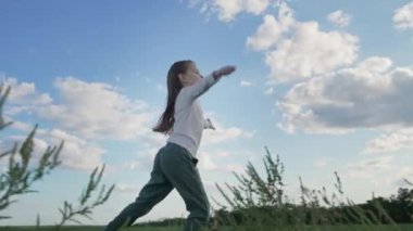 Gün batımında dışarıda dans eden mutlu kız. Çocuk kırsalda ağır çekimde eğleniyor.