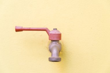 Sarı duvar arka plan üzerinde kırmızı musluk.