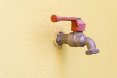 Sarı duvar arka plan üzerinde kırmızı musluk.