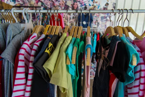 Färgglada blusen hänger på klädstreck i en butik. Stockfoto