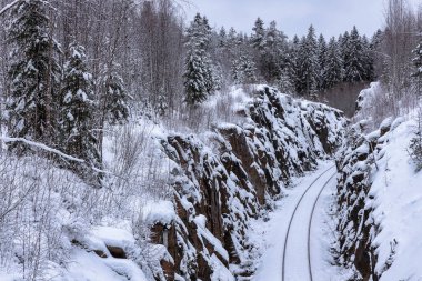 Demiryolu, üzerinde küçük bir yol köprüsü olan kayadaki oyuk bir geçitten geçer.