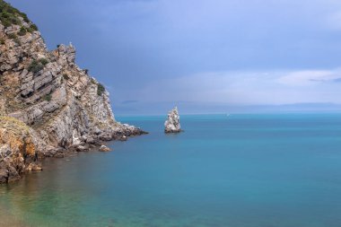 Kayalık sahil üzerindeki dramatik gökyüzü ve Karadeniz kıyısındaki Parus kayası. Kırım Yarımadası