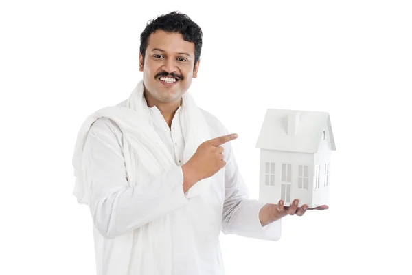 Portrait of a smiling man pointing at a model home — Stock Photo, Image