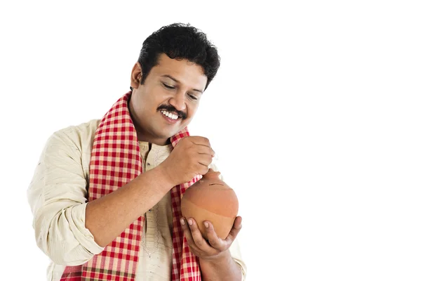 Man putting a coin into a piggy bank and smiling — Stock Photo, Image