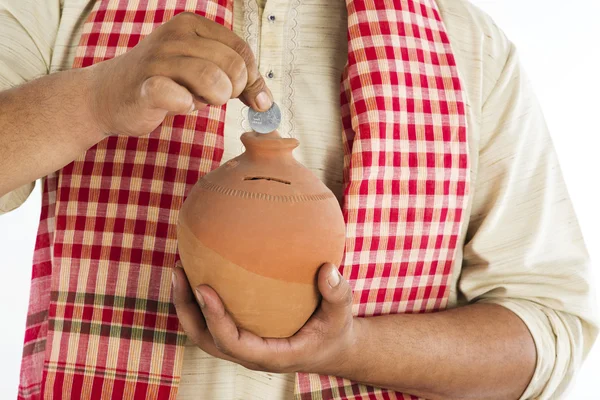 Man putting a coin into a piggy bank — Stock Photo, Image