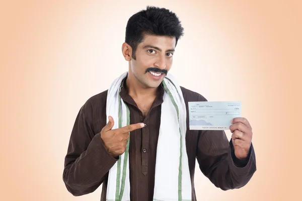 Portrait of a man pointing to a bank cheque and smiling — Stock Photo, Image