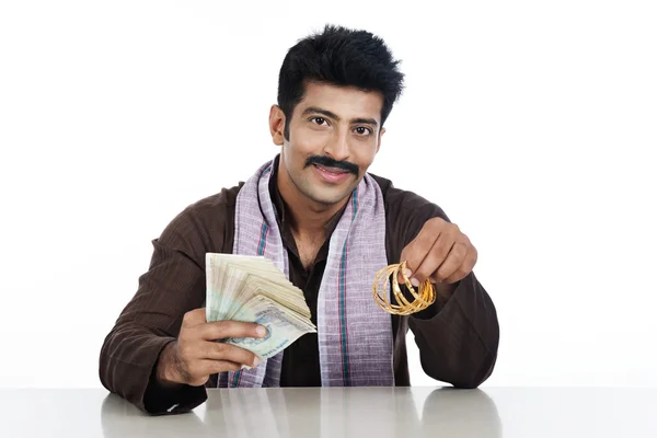 Retrato de un hombre sosteniendo dinero y brazaletes dorados —  Fotos de Stock