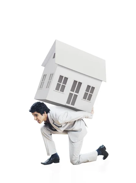 Businessman carrying a model home on his back — Stock Photo, Image