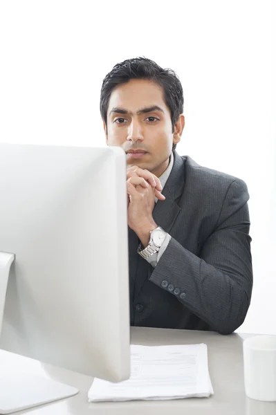 Empresario sentado frente a la computadora y pensando — Foto de Stock