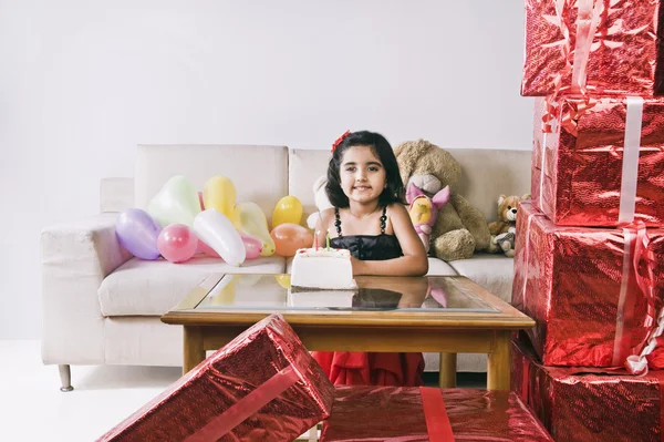 Portrait of a girl standing in front of a cake and smiling — Stock Photo, Image