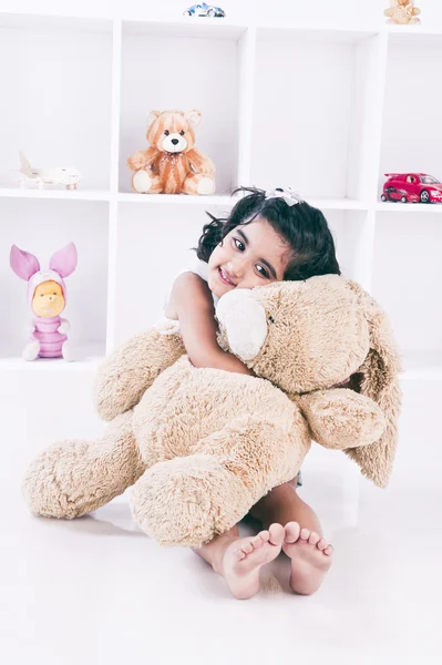 Menina segurando um ursinho de pelúcia e sorrindo — Fotografia de Stock