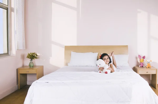 Meisje liggend op het bed met een teddybeer — Stockfoto