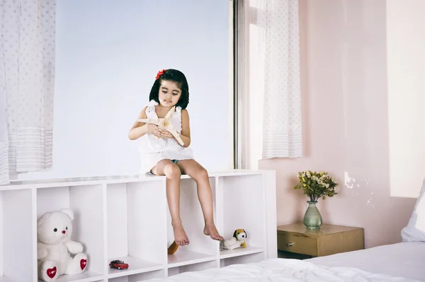 Menina sentada em uma prateleira e brincando com avião de brinquedo — Fotografia de Stock