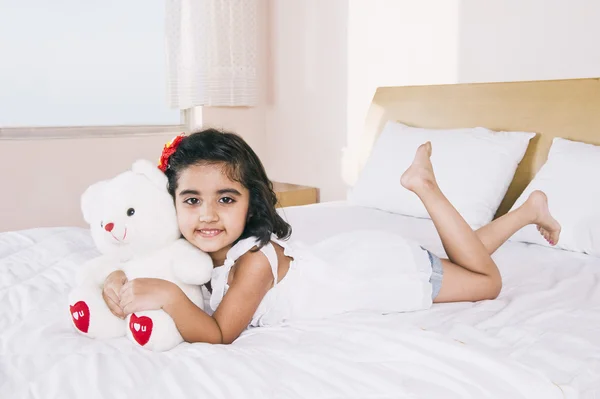Portret dziewczyny, leżąc na łóżku trzymając misia i smi — Zdjęcie stockowe