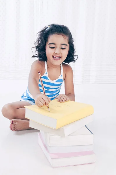 Dziewczyna pisze na książkę z ołówkiem — Zdjęcie stockowe