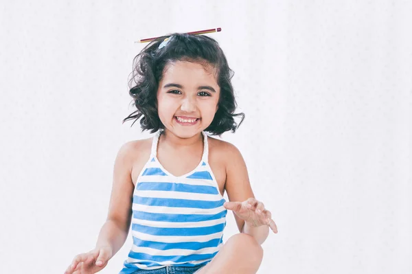 Retrato de uma menina sorrindo com um lápis na cabeça — Fotografia de Stock