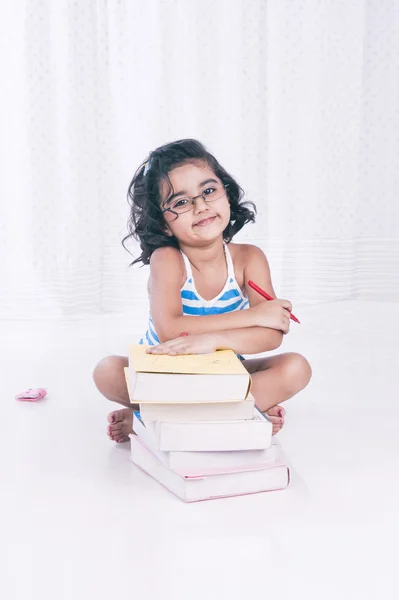 Retrato de uma menina sentada perto de livros e sorrindo Imagens De Bancos De Imagens