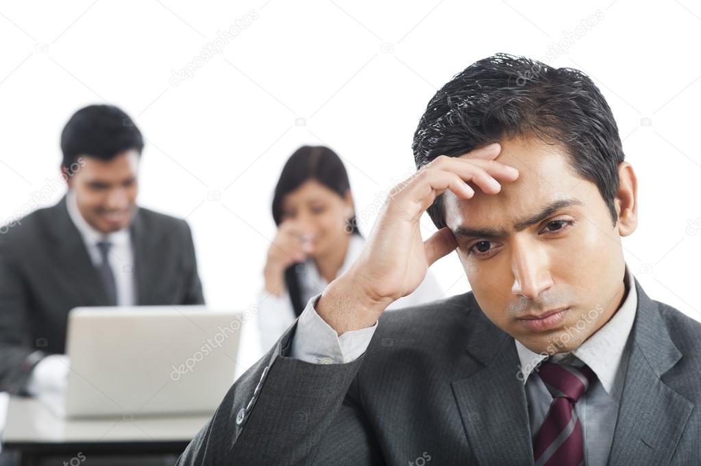 Close-up of a businessman looking upset with his colleagues in t