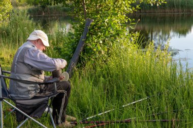 Sakin bir nehrin kıyısında yaşlı bir balıkçı balık tutmayı sever..