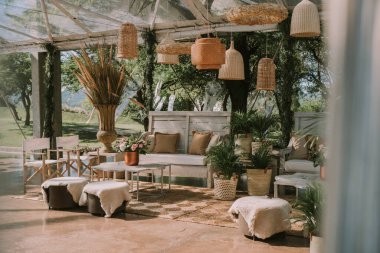 Koltuklar ve bahçe masası tencere, çiçek ve taklit deri kumaşlarla süslenmiş..