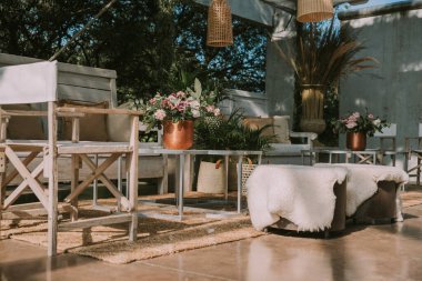 Koltuklar ve bahçe masası tencere, çiçek ve taklit deri kumaşlarla süslenmiş..