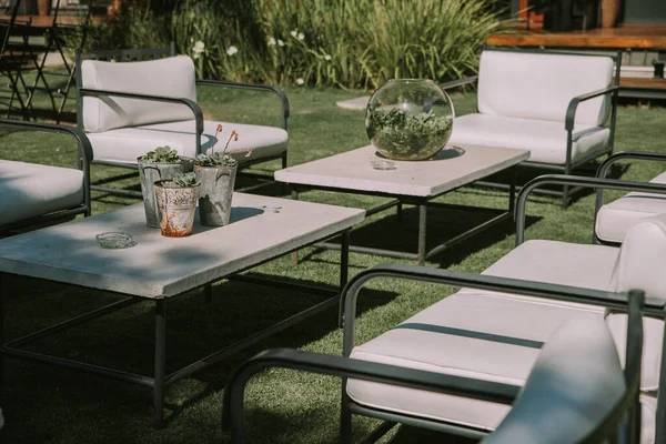 Koltuklar ve bahçe masası tencere, çiçek ve taklit deri kumaşlarla süslenmiş..