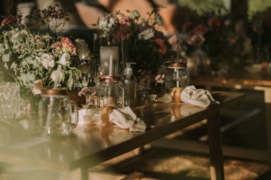 Kişisel bardakları, mumları ve çiçekleri olan ahşap bir masa. Sosyal etkinlikler için dekorasyon.