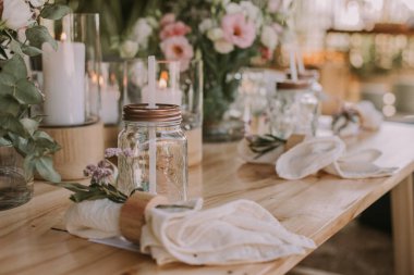 Kişisel bardakları, mumları ve çiçekleri olan ahşap bir masa. Sosyal etkinlikler için dekorasyon.