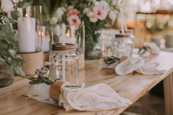 Kişisel bardakları, mumları ve çiçekleri olan ahşap bir masa. Sosyal etkinlikler için dekorasyon.