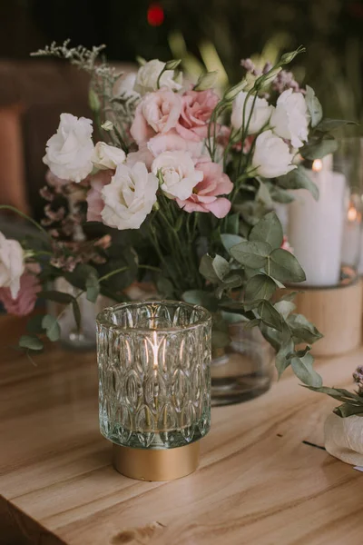 Kişisel bardakları, mumları ve çiçekleri olan ahşap bir masa. Sosyal etkinlikler için dekorasyon.