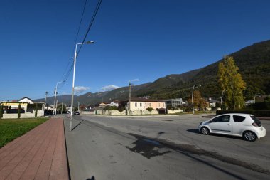 Dağın yanındaki caddeden aşağı doğru giden bir araba.