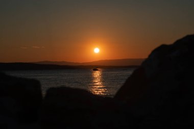 Batan güneşin parıltısında bir tekne.