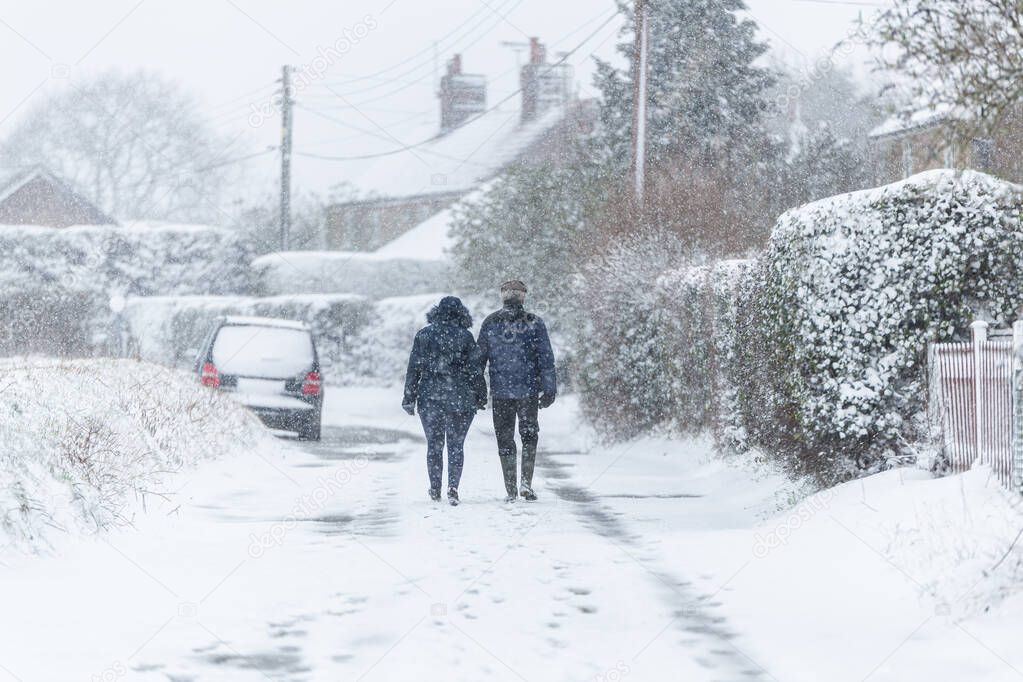 A couple taking a walking during a snowstorm blizzard. Beast from the east 2021, extreme weather