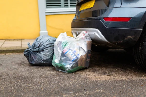 Woodbridge, Suffolk, İngiltere 1 Mart 2021: Park halindeki bir arabanın arkasında çöp dolu plastik torbalar