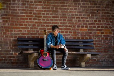 Woodbridge, Suffolk, İngiltere 13 Eylül 2020: 20 'li yaşlarda bir kadın dışarıda akustik gitar çalıyor ve yoldan geçenleri de dinliyor.