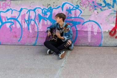 Woodbridge, Suffolk, İngiltere 13 Eylül 2020: 20 'li yaşlarda bir kadın dışarıda akustik gitar çalıyor ve yoldan geçenleri de dinliyor.