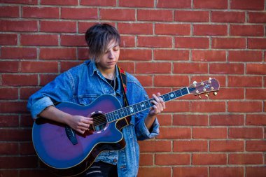 Woodbridge, Suffolk, İngiltere 13 Eylül 2020: 20 'li yaşlarda bir kadın dışarıda akustik gitar çalıyor ve yoldan geçenleri de dinliyor.