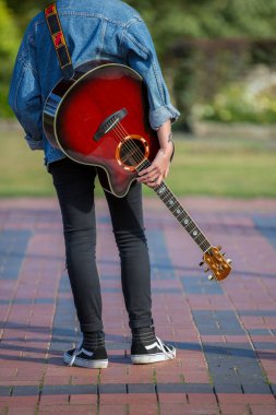 Woodbridge, Suffolk, İngiltere 13 Eylül 2020: 20 'li yaşlarda akustik gitarıyla rahatlayan ve poz veren bir kadın